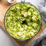 Shredded brussels sprouts in food processor bowl.