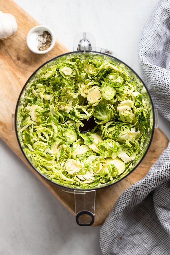 Shredded brussels sprouts in food processor bowl.