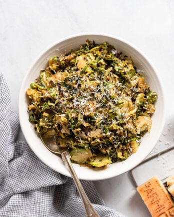 Bowl of shredded brussels sprouts with parmesan and spoon.