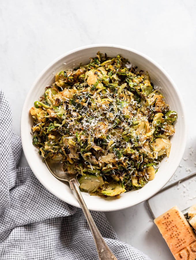 Bowl of shredded brussels sprouts with parmesan and spoon.