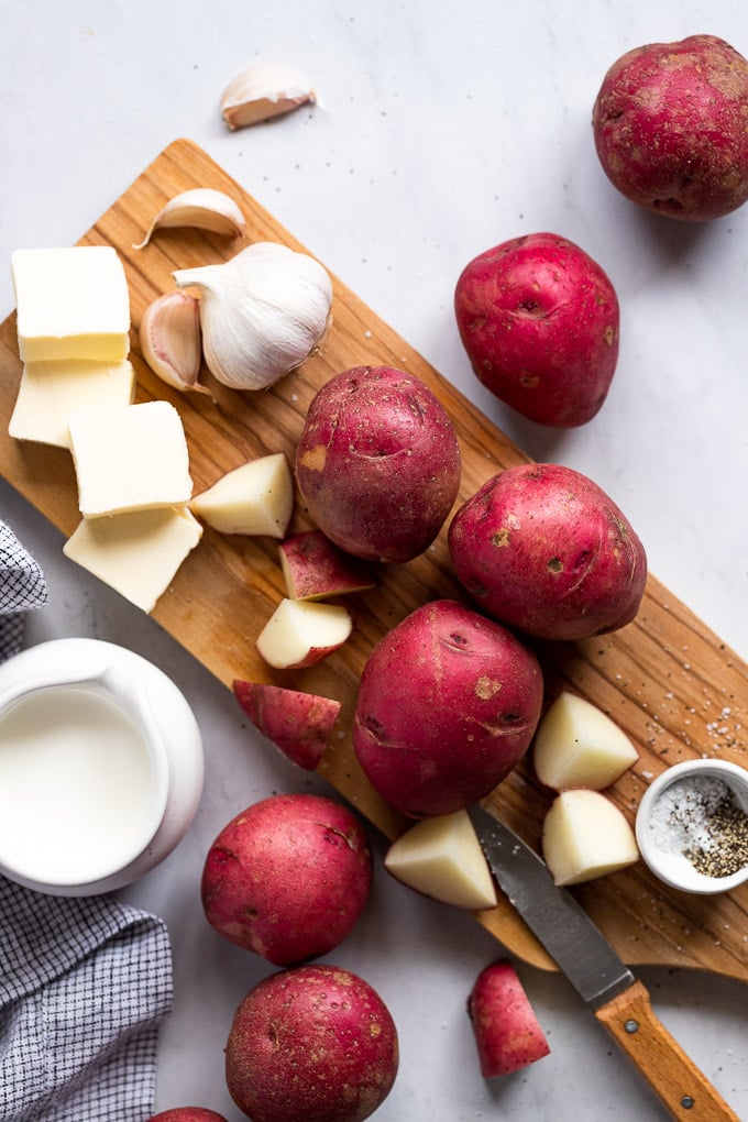 Potatoes, butter, cream, and garlic on cutting board.