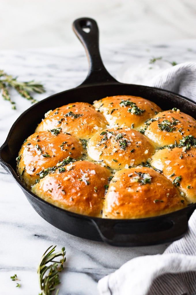 Homemade rolls in cast iron skillet with garlic and herbs on top.