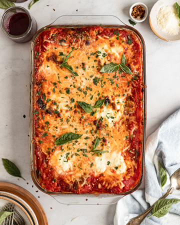 Casserole pan with baked spaghetti garnished with basil.