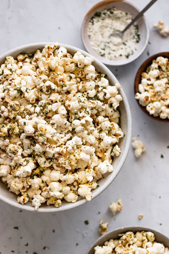Popcorn in bowls next to seasoning.