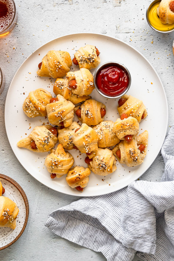 Pigs in a blanket on plate with ketchup.