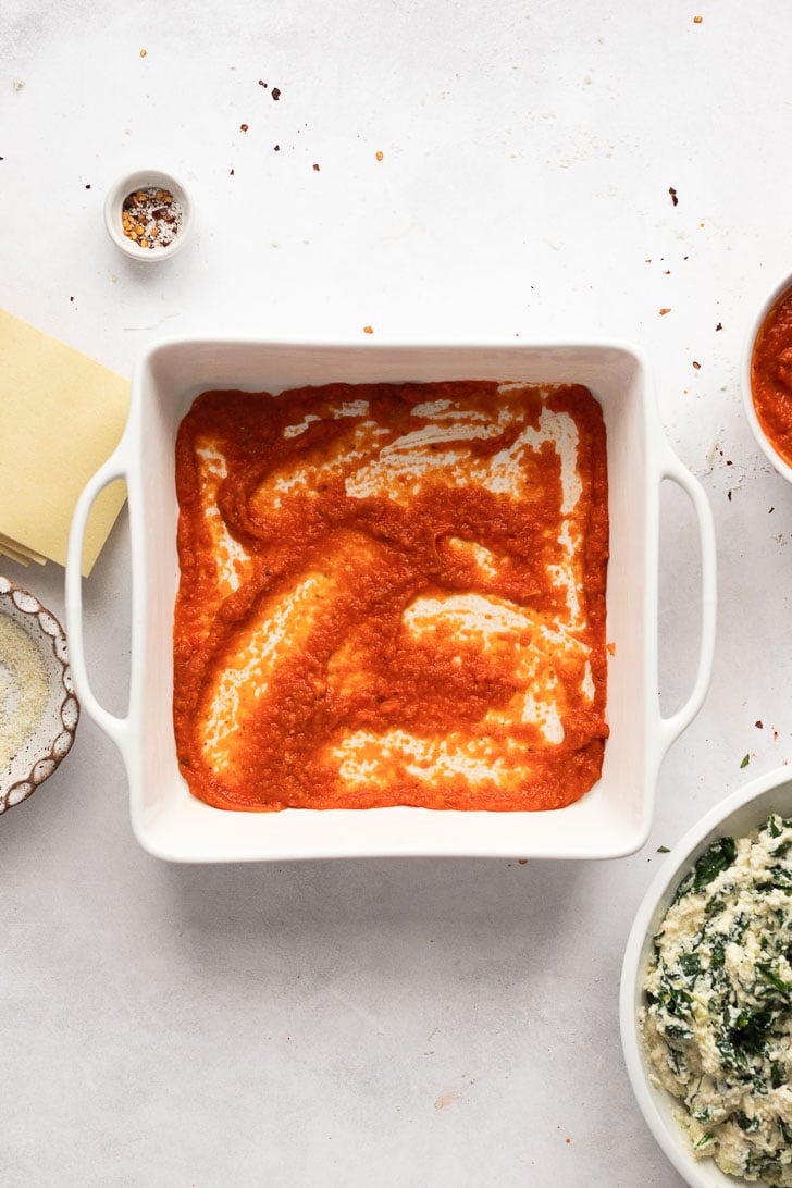 Pasta sauce spread on bottom of pan.