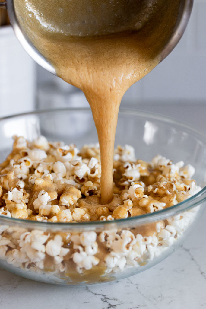 Pouring caramel into bowl of popcorn.