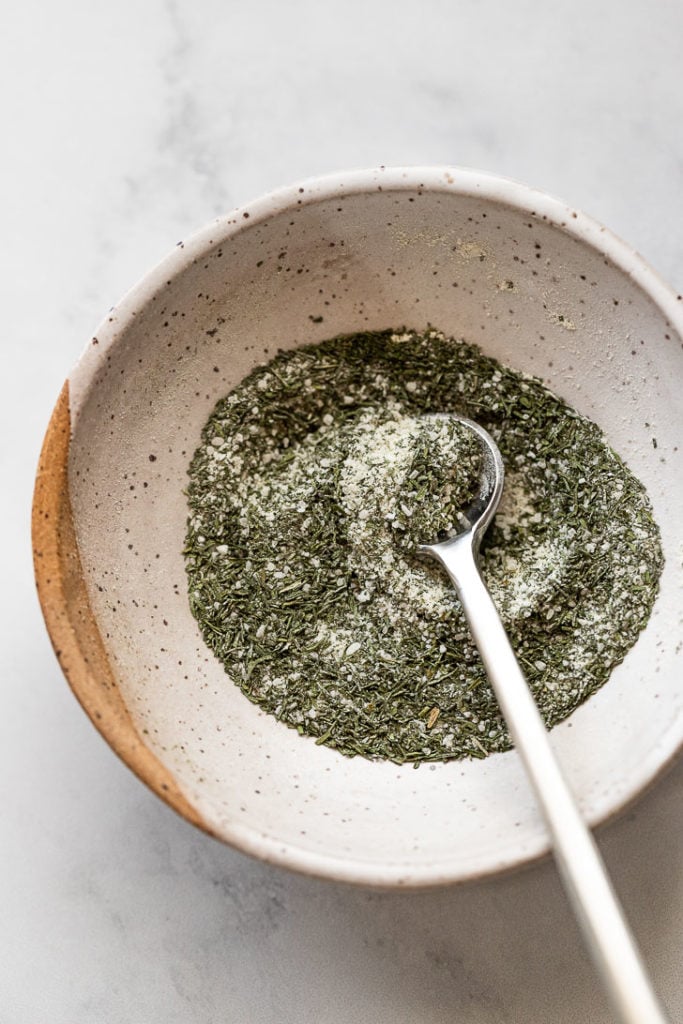 Bowl of dill seasoning with spoon.