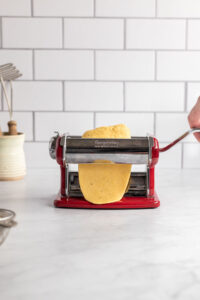 Rolling dough through pasta machine first time.