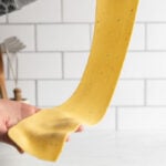 Thinly rolled pasta sheet held between two hands.