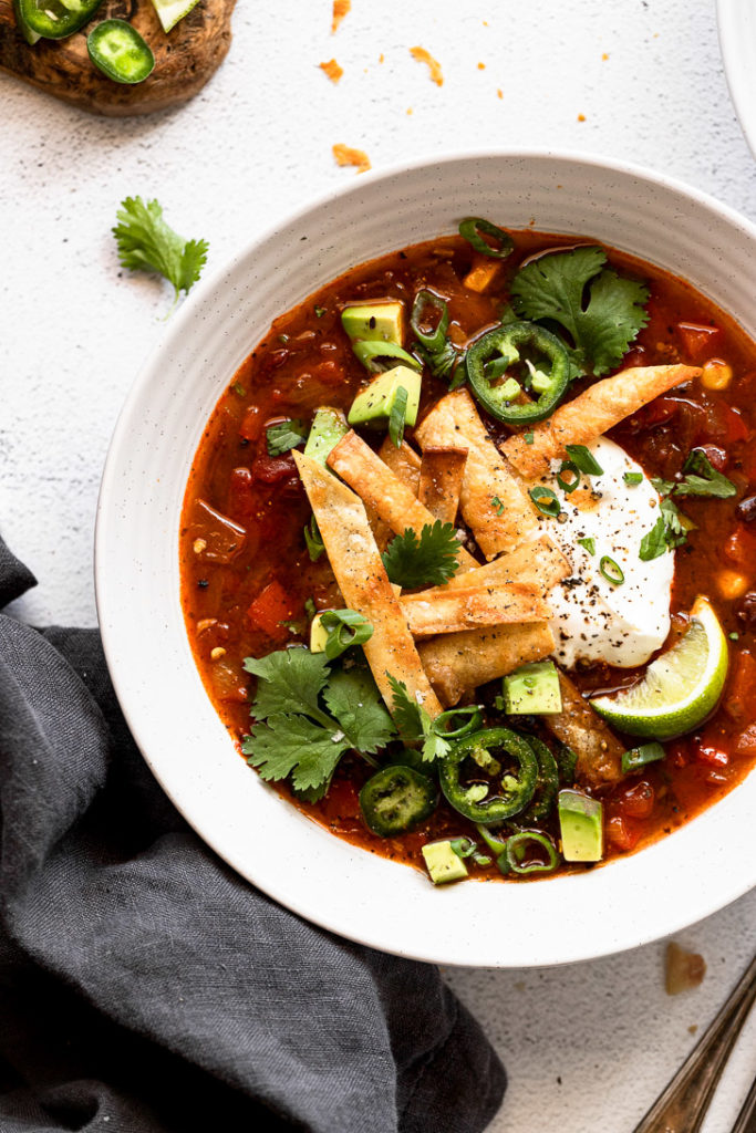 Up close bowl of vegetarian tortilla soup with garnishes.