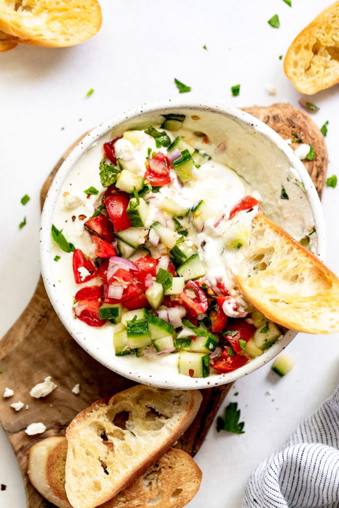 Bowl of whipped feta with greek bruschetta topping.