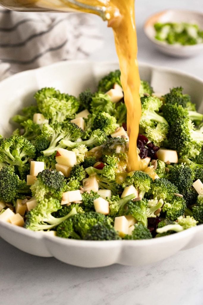 Dressing pouring onto broccoli salad without bacon.