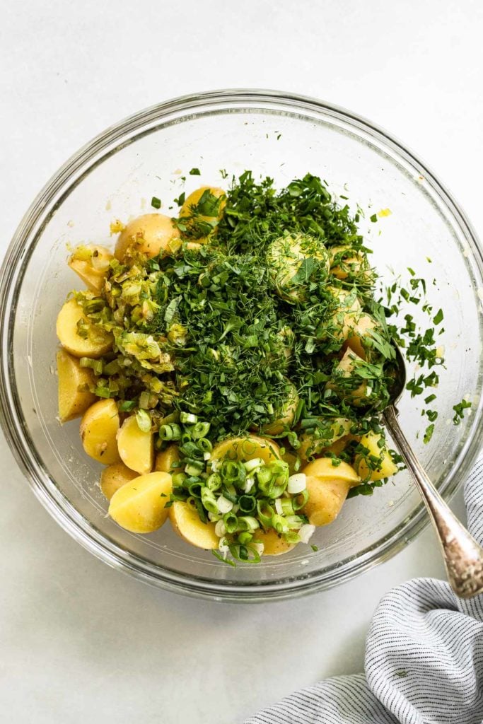 Bowl of potatoes with herbs on top and spoon.