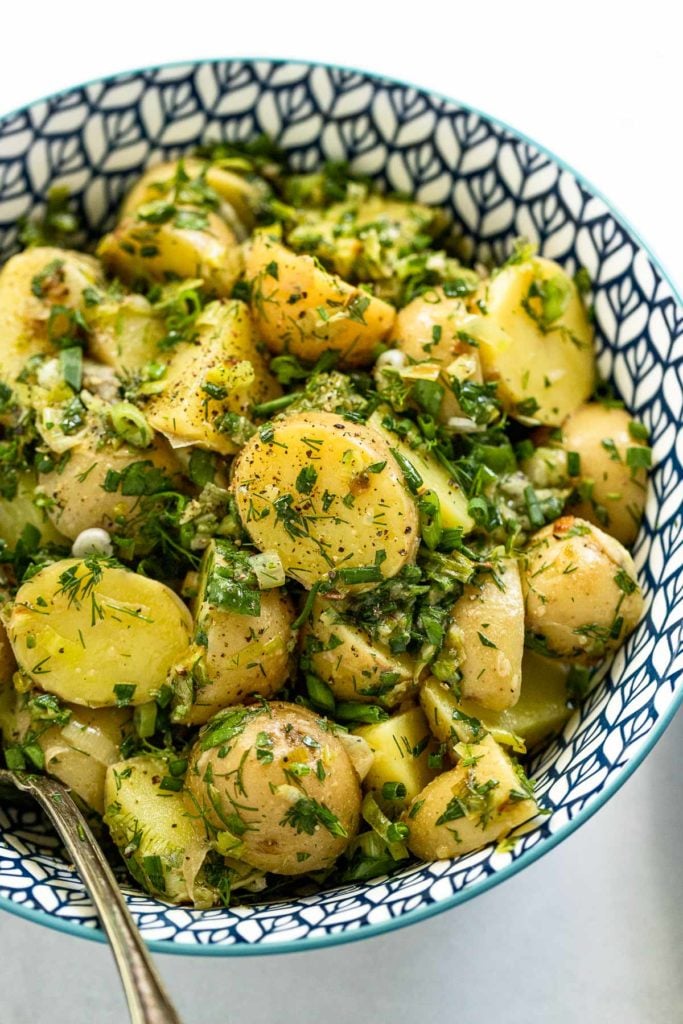 Herb and leek potato salad in blue bowl with spoon.