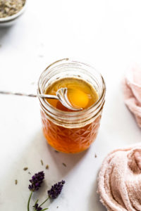 Spoon in jar of lavender honey syrup.