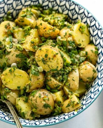 Herb and leek potato salad in blue bowl with spoon.