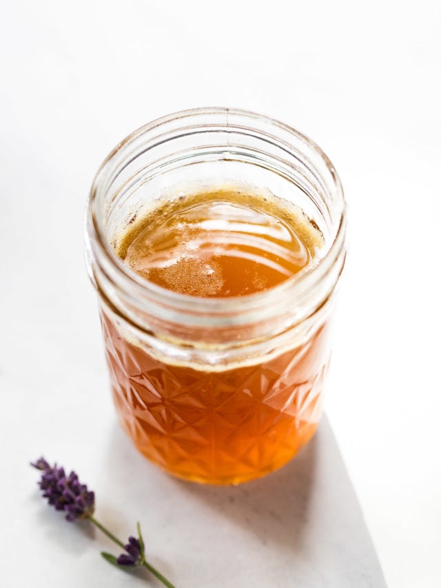 Jar of Lavender Honey Syrup next to lavender sprigs.