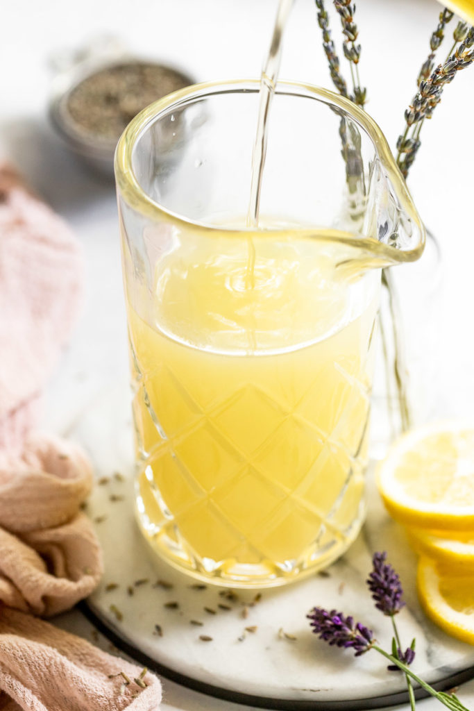 Simple syrup pouring into pitcher of lemonade.