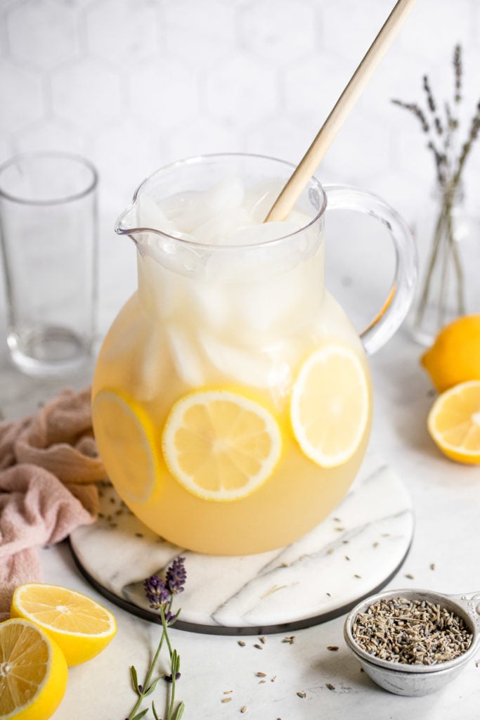 Pitcher of lavender lemonade with spoon and lemon slices.
