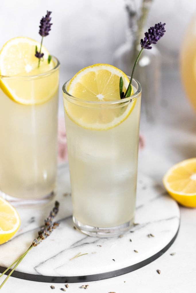 Two glasses of lavender lemonade with lemon slice and lavender sprig.
