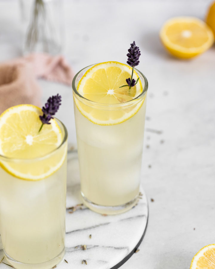 Two glasses of lavender lemonade on marble tray.