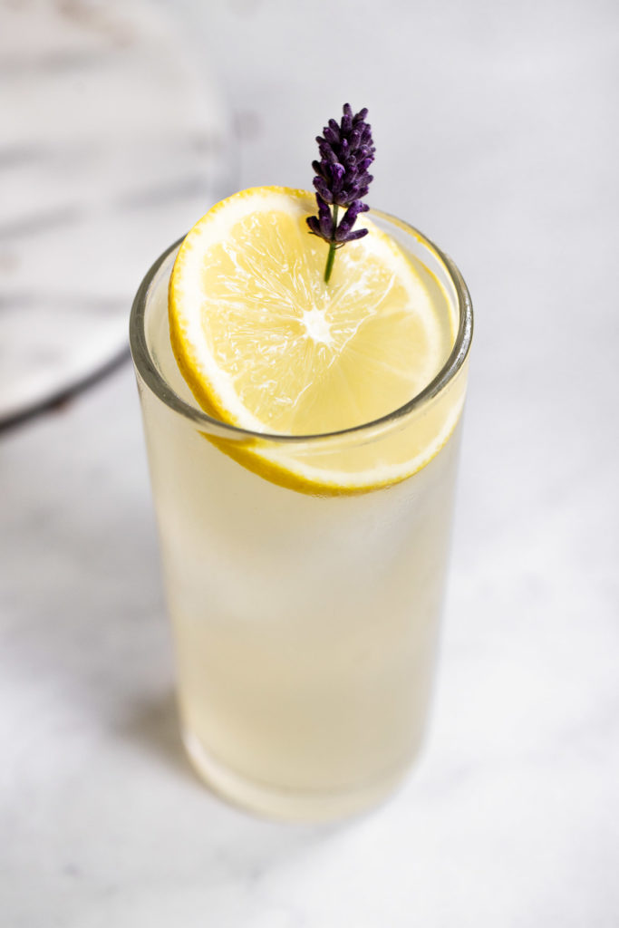 Glass of lemonade with lemon slice and sprig of lavender.