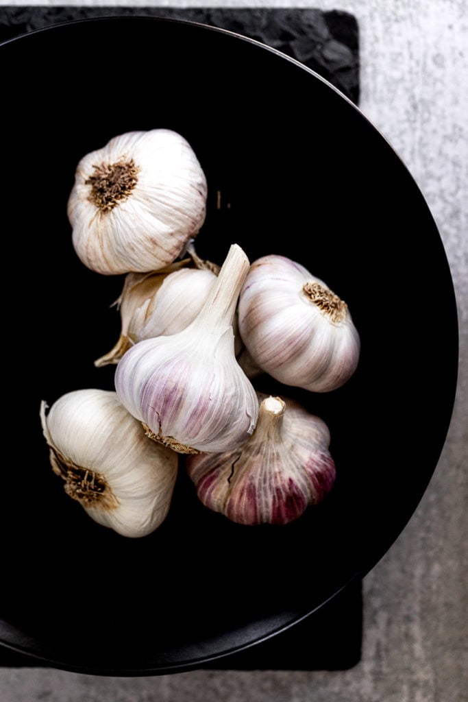 Garlic bulbs in black bowl.
