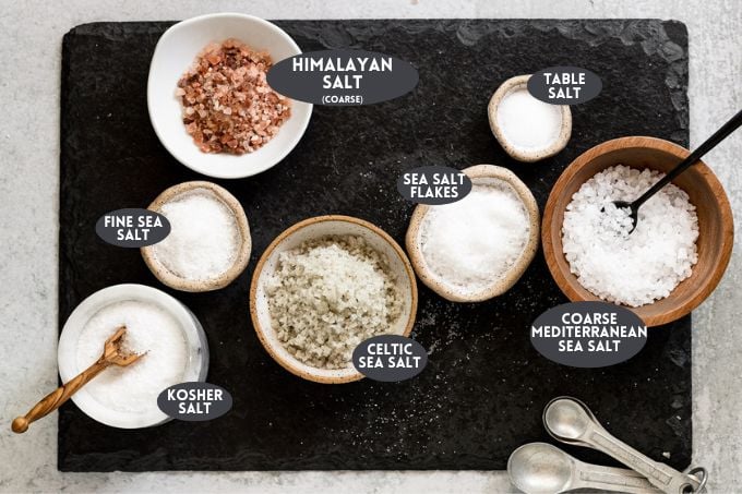 Various salts in small bowls on board with text overlay.
