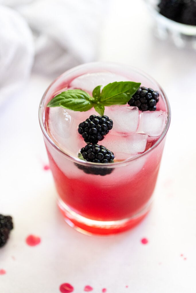 Drink made with blackberry syrup topped with blackberries and basil.