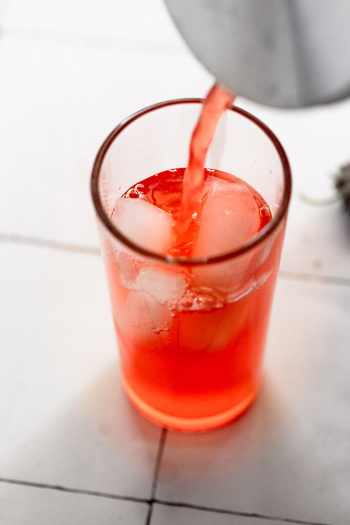 Pouring strawberry lemonade into glass
