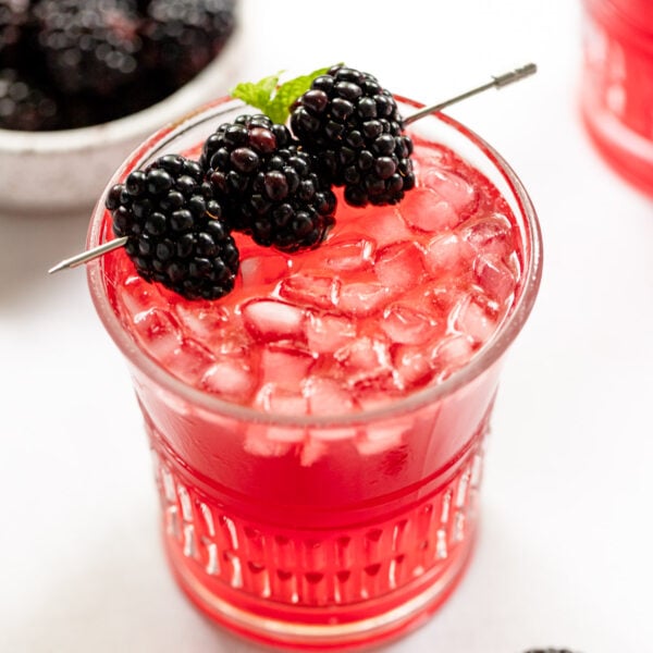 Blackberry bramble cocktail in glass with blackberry garnish.