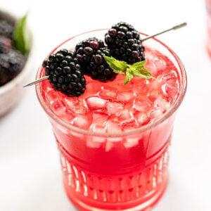 Blackberry bramble cocktail with blackberries in bowl.