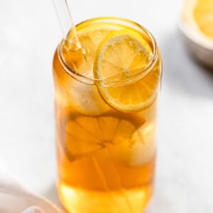 Glass of cold brew iced tea with lemon slices and straw.