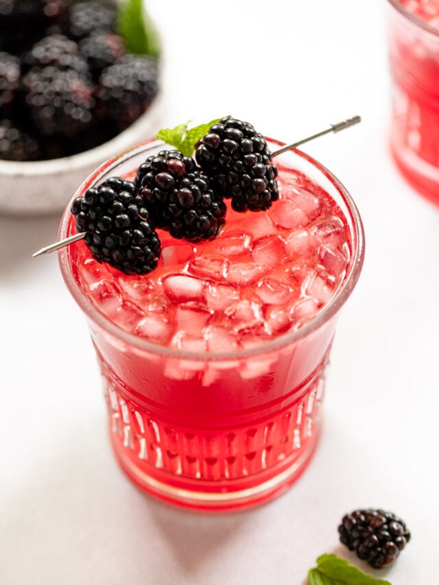 Blackberry bramble cocktail in glass with blackberry garnish.