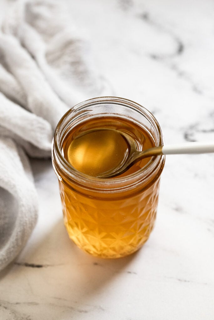 Jar of caramel simple syrup with spoon.