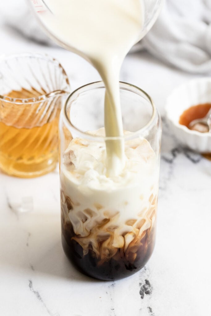 Milk pouring into caramel iced latte.