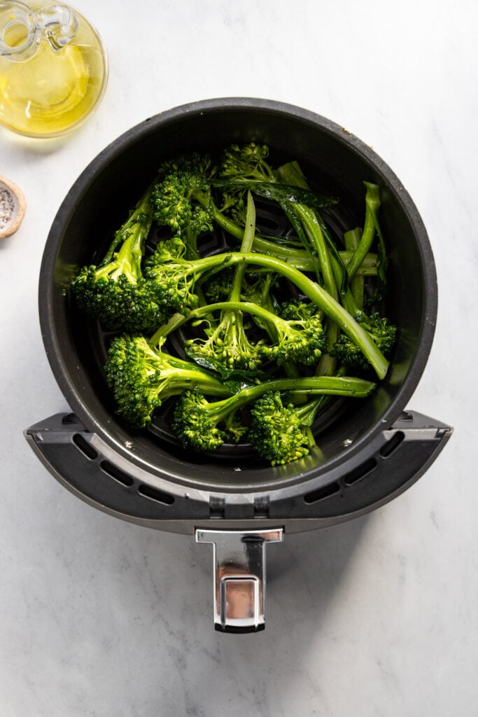 Broccolini in air fryer basket before cooking.