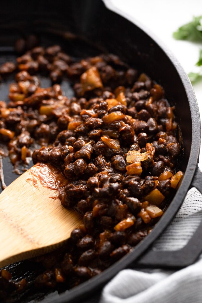 Skillet with spicy black beans and spoon.