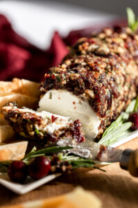 Slice of goat cheese log with cranberry on tray.