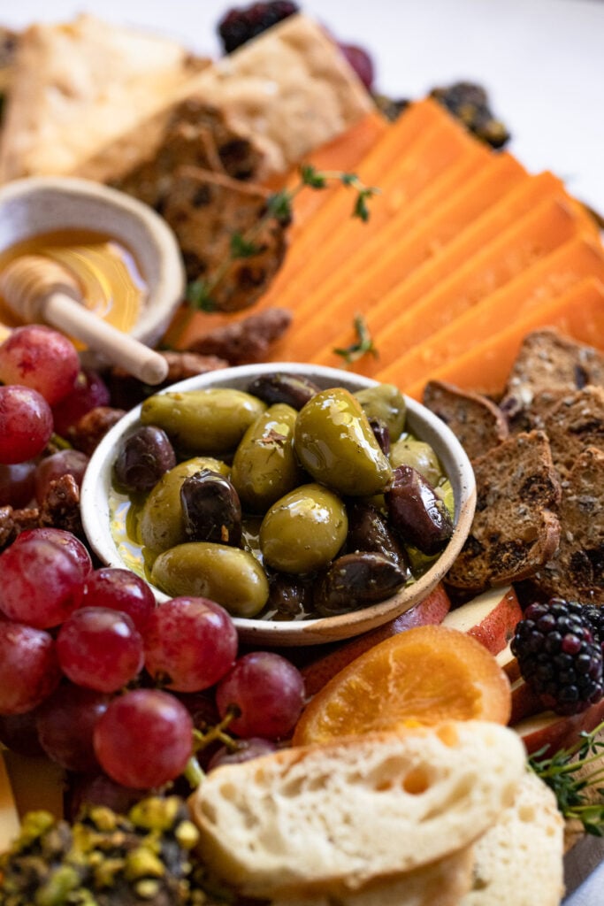 Bowl of olives on cheeseboard.