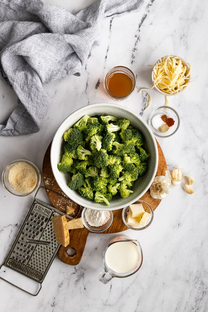 Broccoli florets in bowl surrounded by bowls of other ingredients.