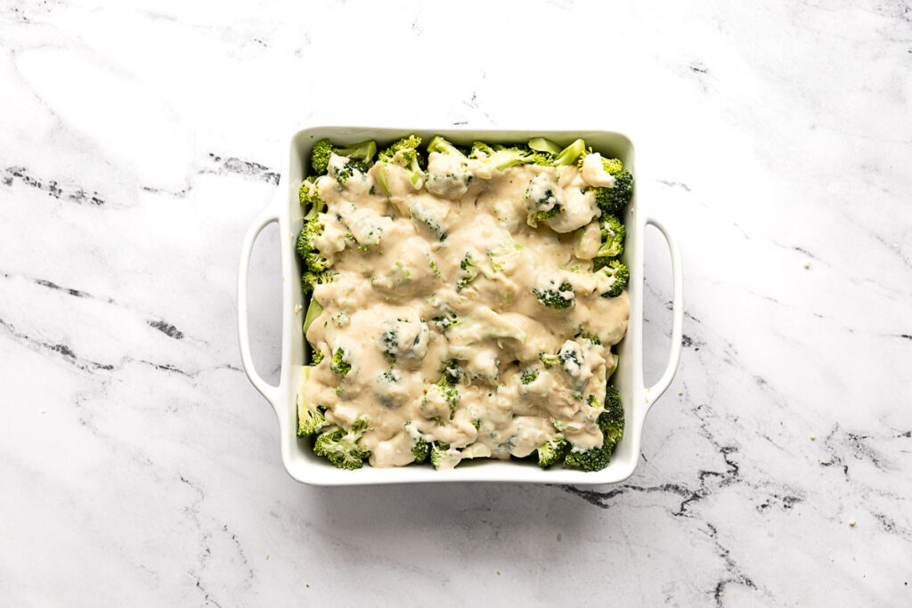Broccoli in dish with cheese sauce on top.