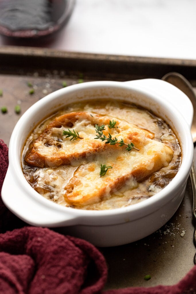 Side view of soup with cheesy bread on top.