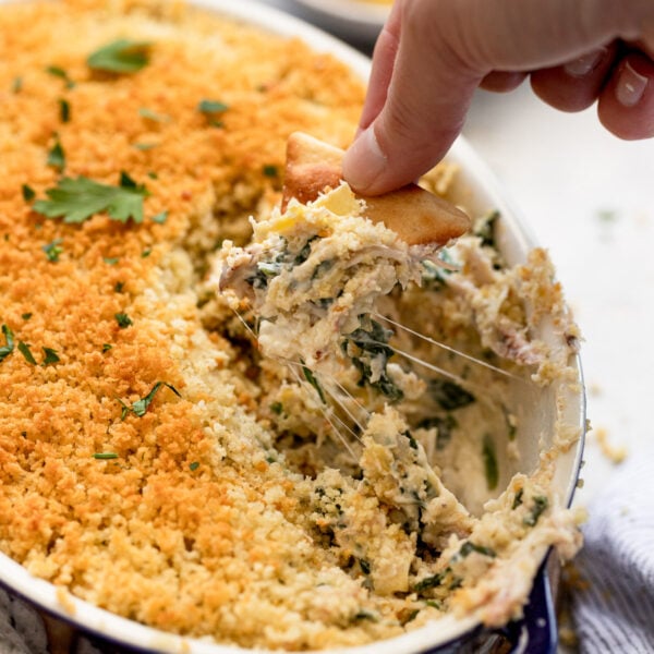 Hand dipping cracker into crab dip.