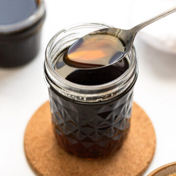 Jar of brown sugar simple syrup with spoon taking scoop.