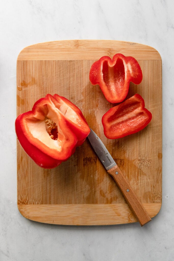 Red bell pepper on cutting board with two sides sliced off.
