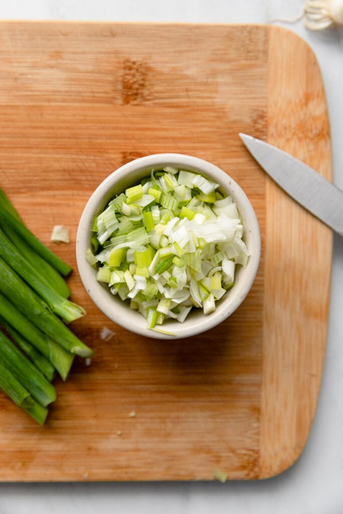 Bowl of finely chopped green onion on cutting board.