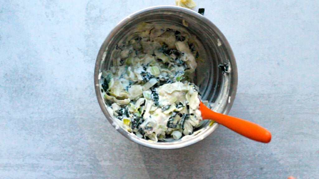 Bowl with cheesy kale artichoke mixture.