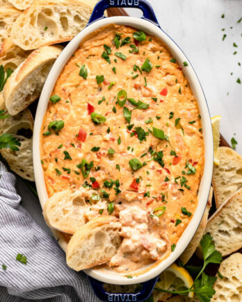 Shrimp dip in baker with two baguette slices dipped in.